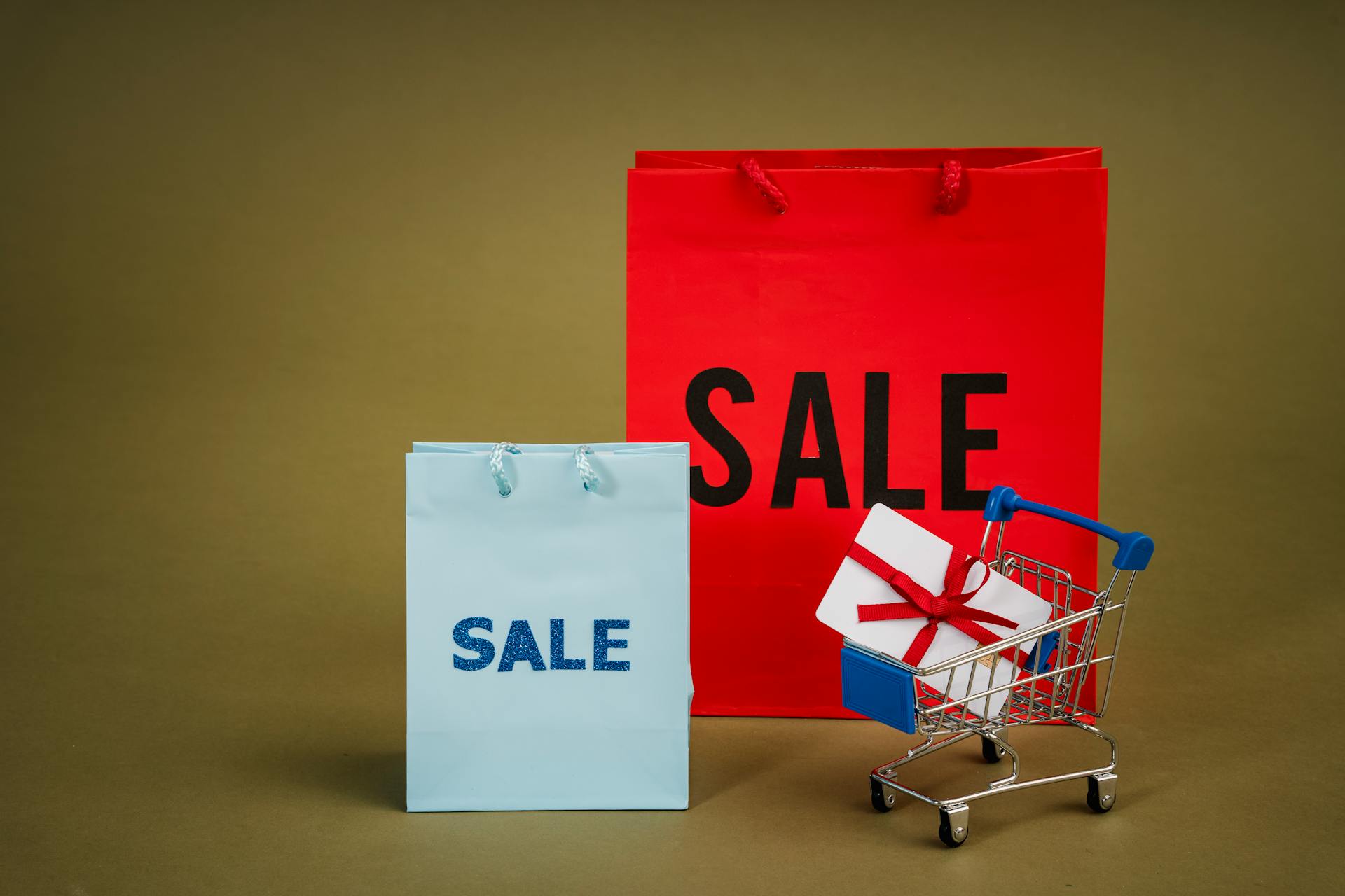 Winkelwagentje en tasjes met korting erop geschreven en een cadeaubon met een strik